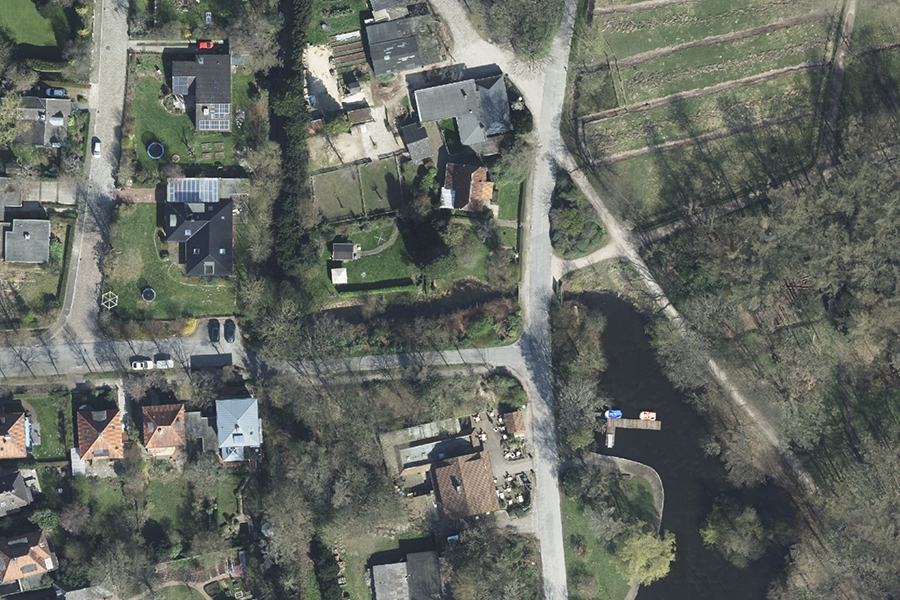 Luftbild einer ländlichen Siedlung mit Wohnhäusern, Teich und Gärten