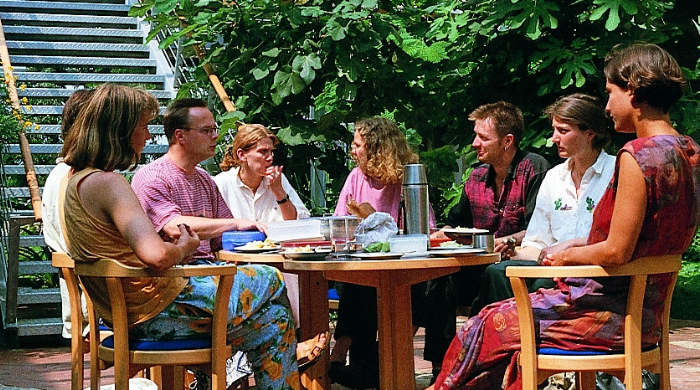 Gruppe von Menschen in einer Sitzgruppe im begrünten Innenhof, umgeben von Pflanzen
