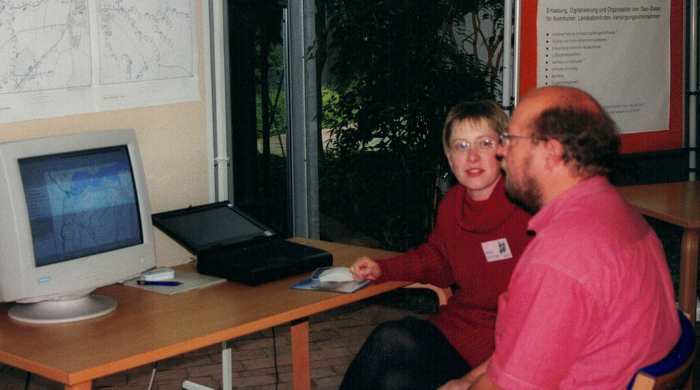 Mann und Frau diskutieren über GIS-Daten auf einem Computerbildschirm